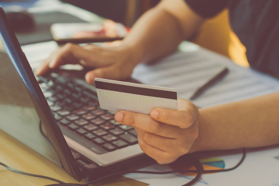 Hands holding a credit card at a laptop, buying online