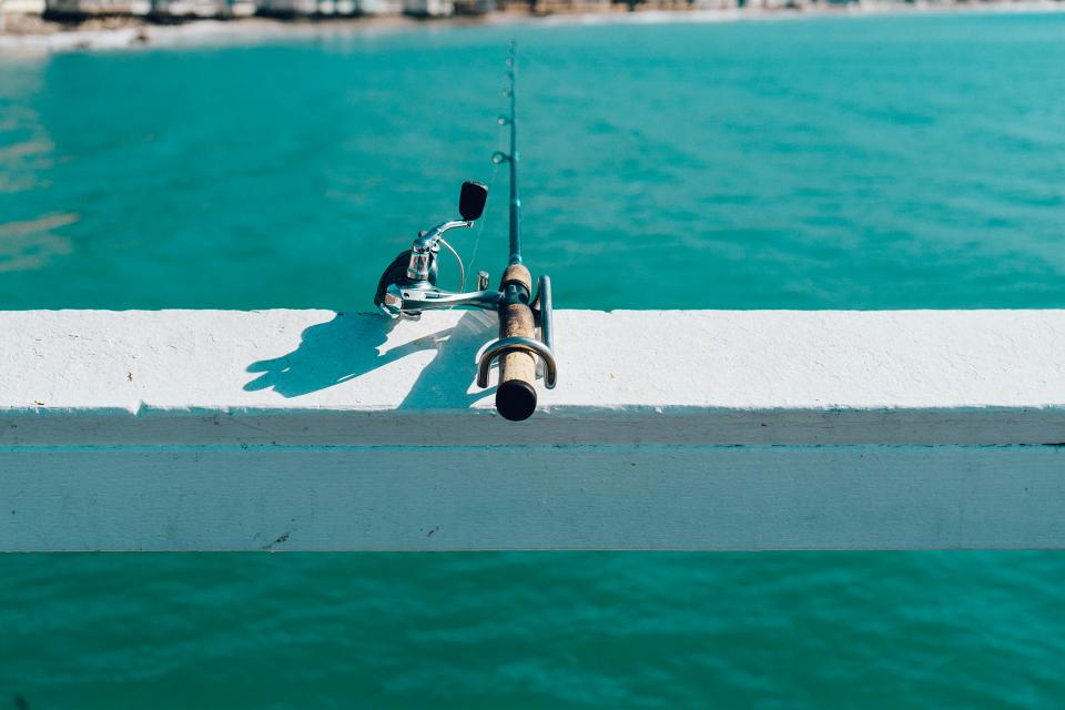 Fishing rod resting on a pier rail over teal water, a metaphor for offers that aren't converting